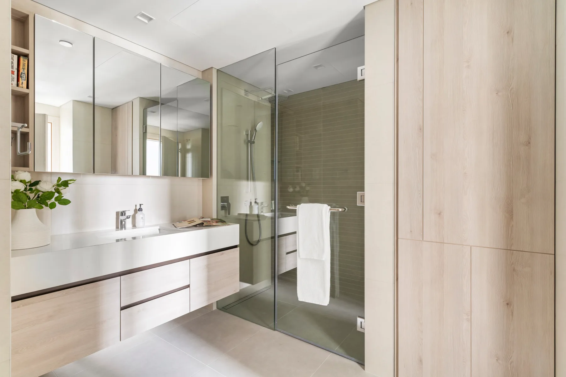 A modern bathroom with a long vanity and a glass shower.