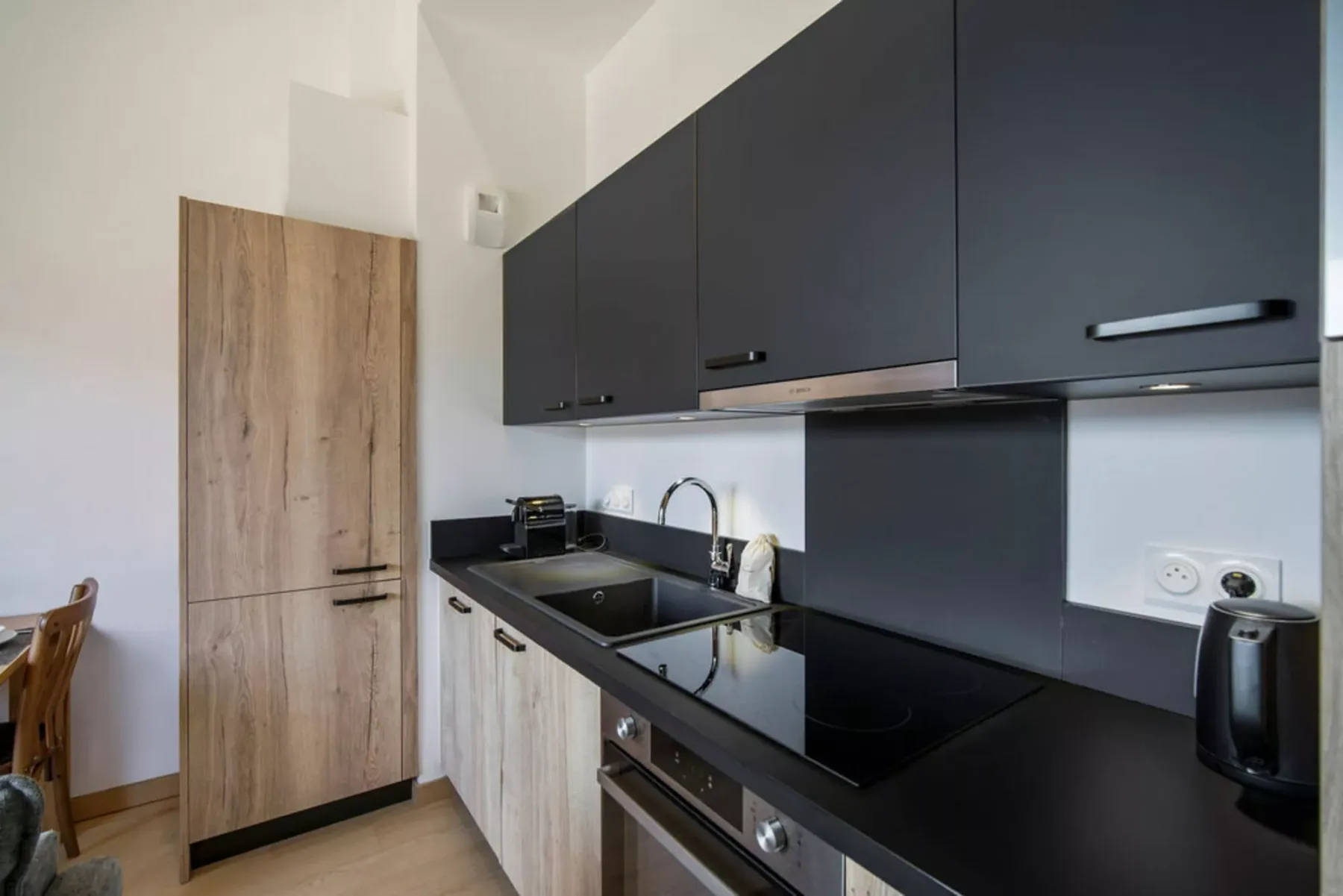 A modern kitchen with dark cabinets and a black countertop.