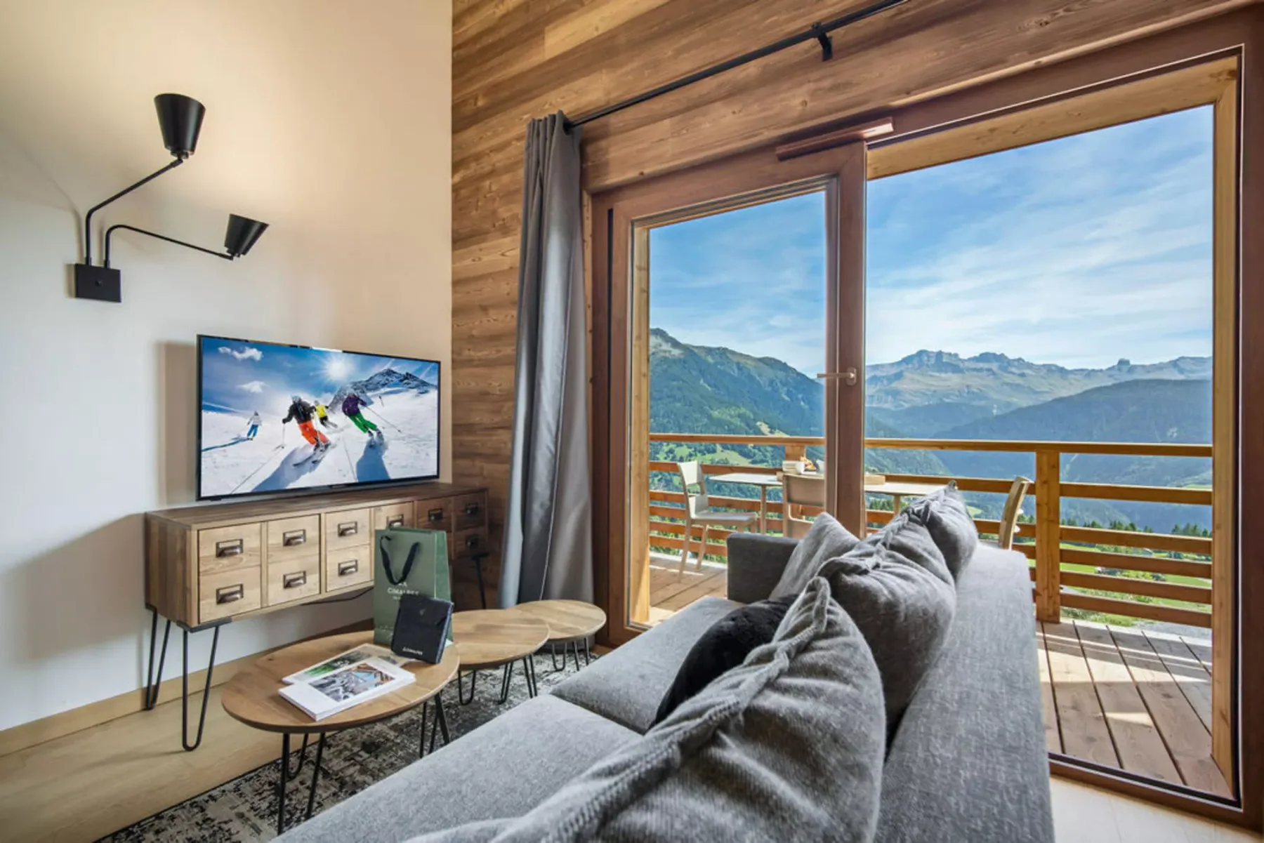A living room with seating beside large windows overlooking a mountain landscape.
