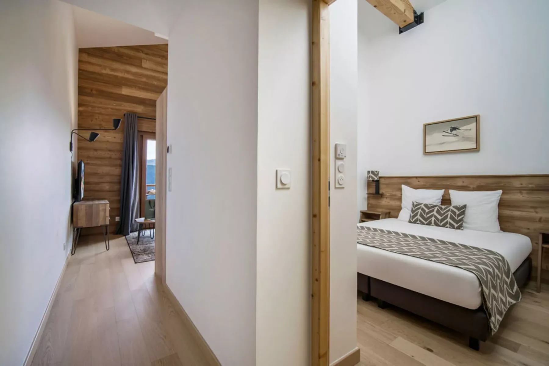 A bedroom with a neatly made bed and a wood-paneled wall.