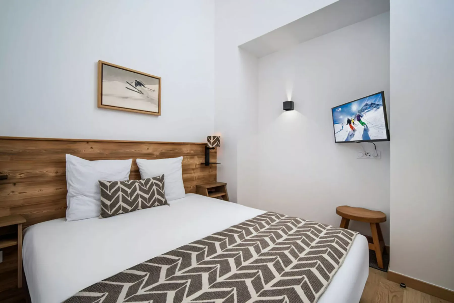 A bedroom with a neatly made bed, patterned blanket, and wood headboard.