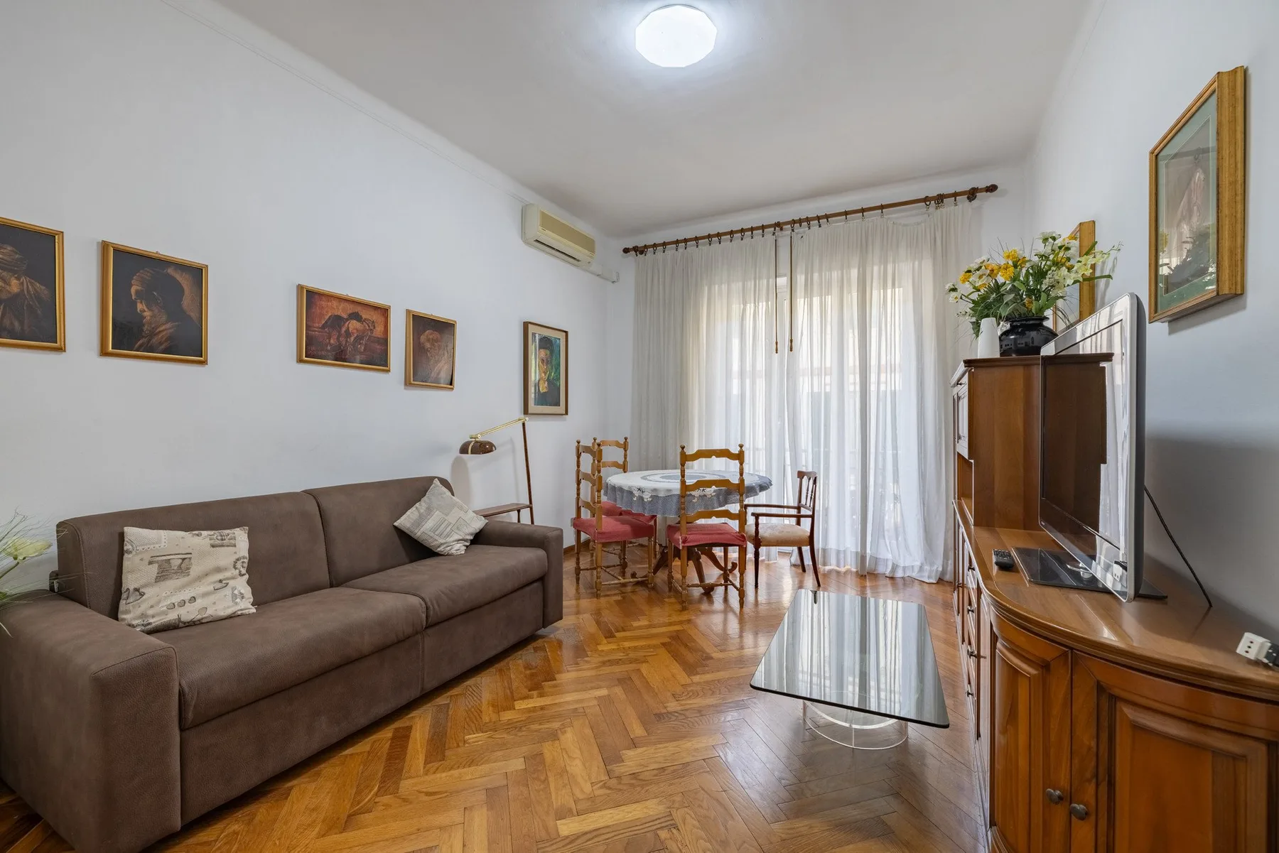 Una sala de estar con asientos, una mesa de comedor y un televisor.