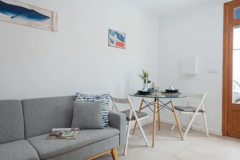 A bright living and dining area with a gray sofa and a small table.