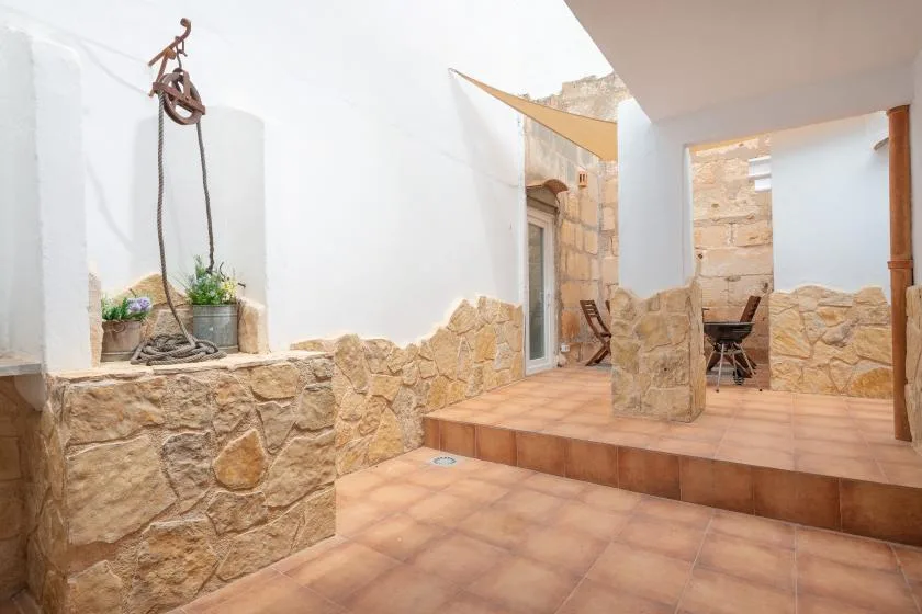 A tiled interior courtyard has stone walls, a raised platform, and a small table.