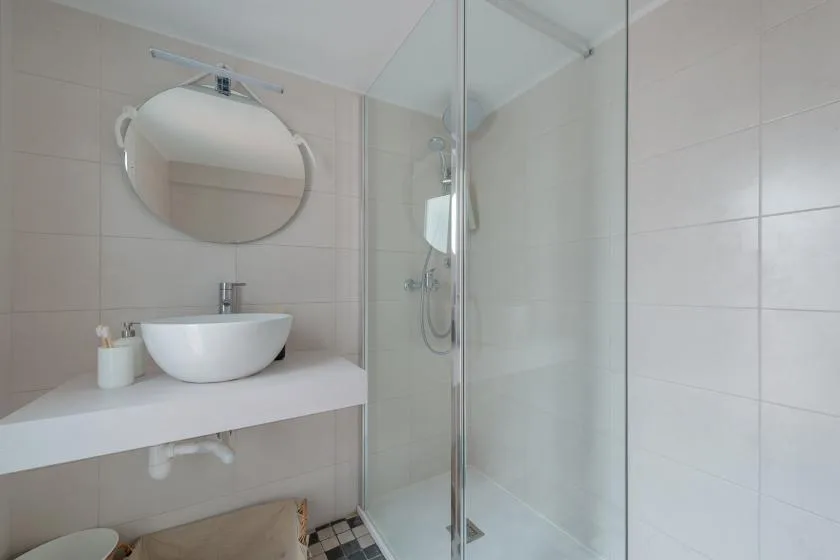 A bright tiled bathroom with a vessel sink and glass shower.