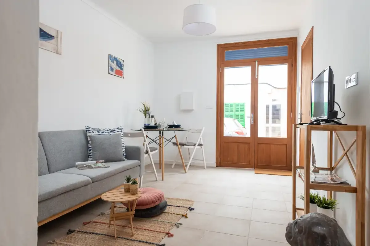 A bright living room with seating, a small table, and a wooden-framed glass door.