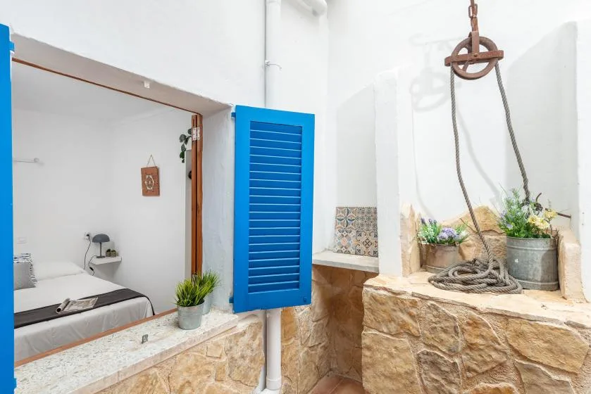 A tiled bathroom with a shower area, blue shutters, and potted plants.