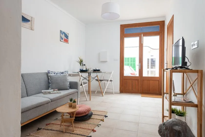 A bright living room with a gray sofa and wooden doors.
