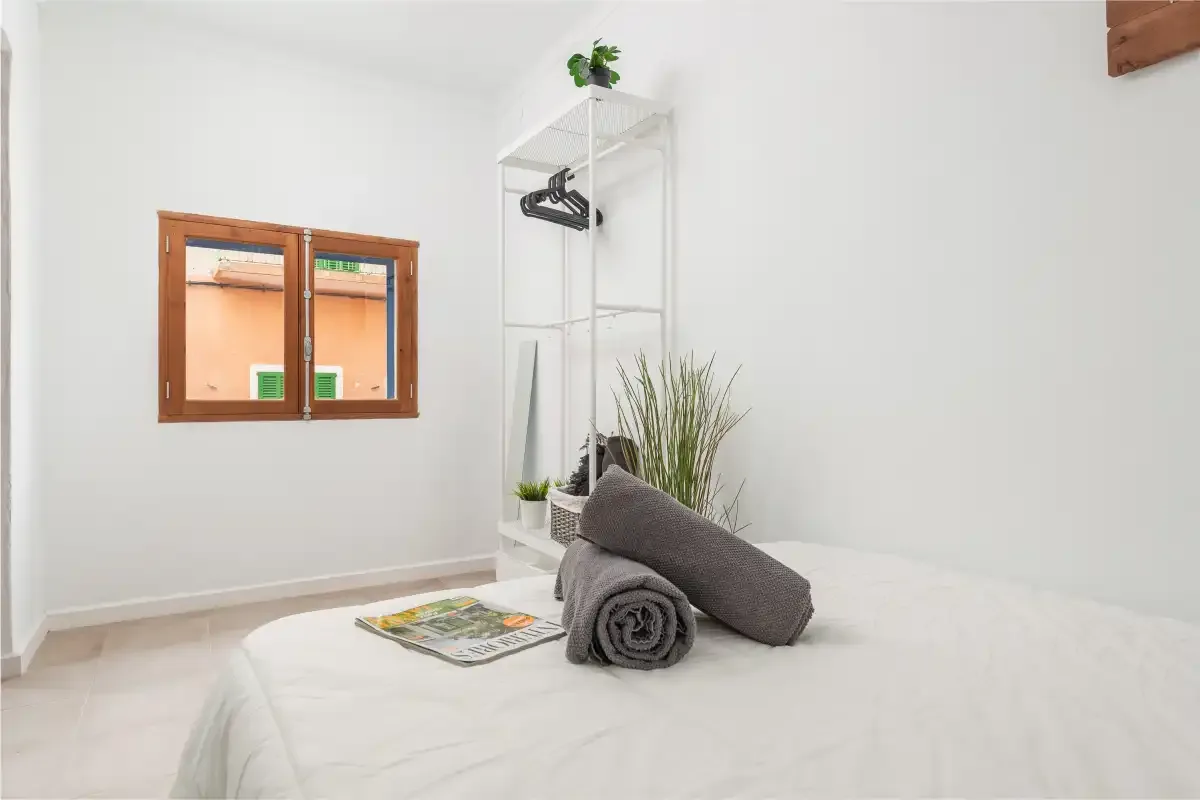A bedroom with a neatly made bed and a small window.