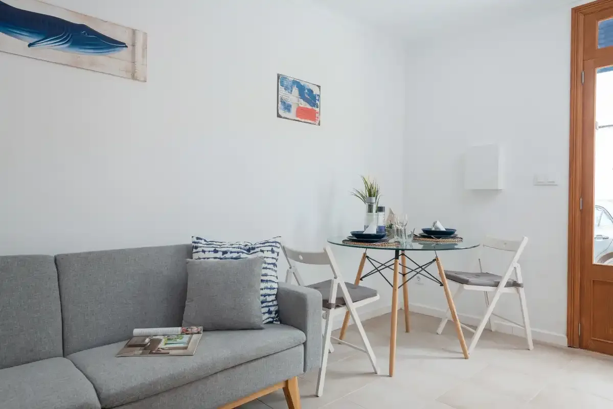 A bright living and dining area with gray seating and a table by the window.