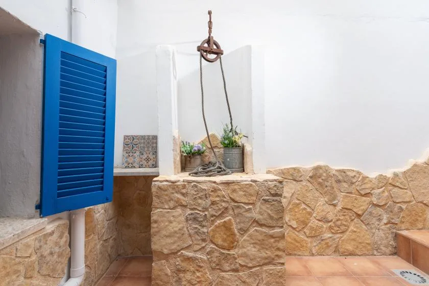 A stone-lined indoor water feature with a blue shutter on the wall.