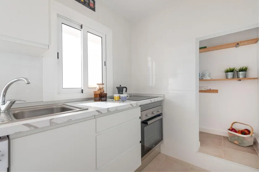A bright kitchen with a countertop, sink, and built-in oven.