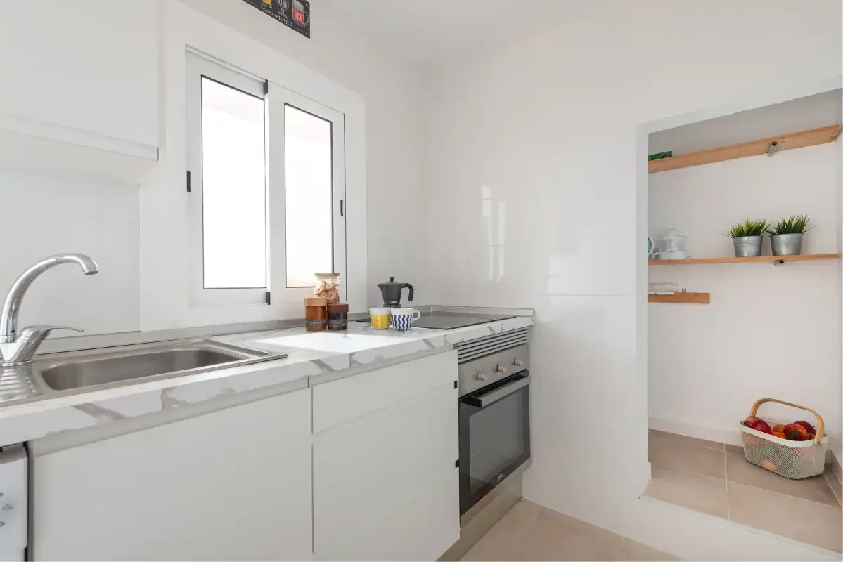 A bright kitchen with white cabinets, a sink, and an oven.
