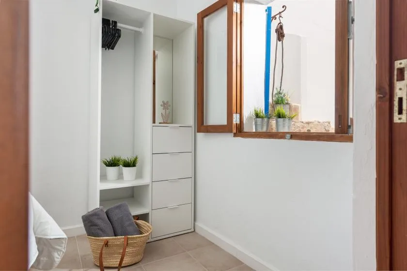 A bright dressing area with open wardrobes and a wooden-framed mirror.