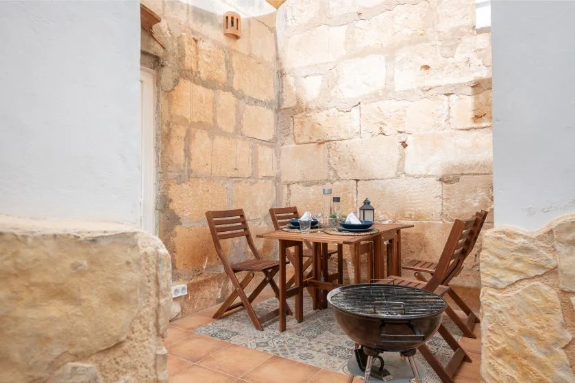 A dining area with a wooden table and chairs beside pale stone walls.