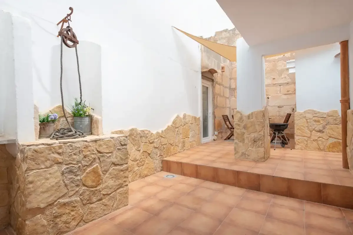 A tiled patio with stone walls, a raised seating area, and potted plants.