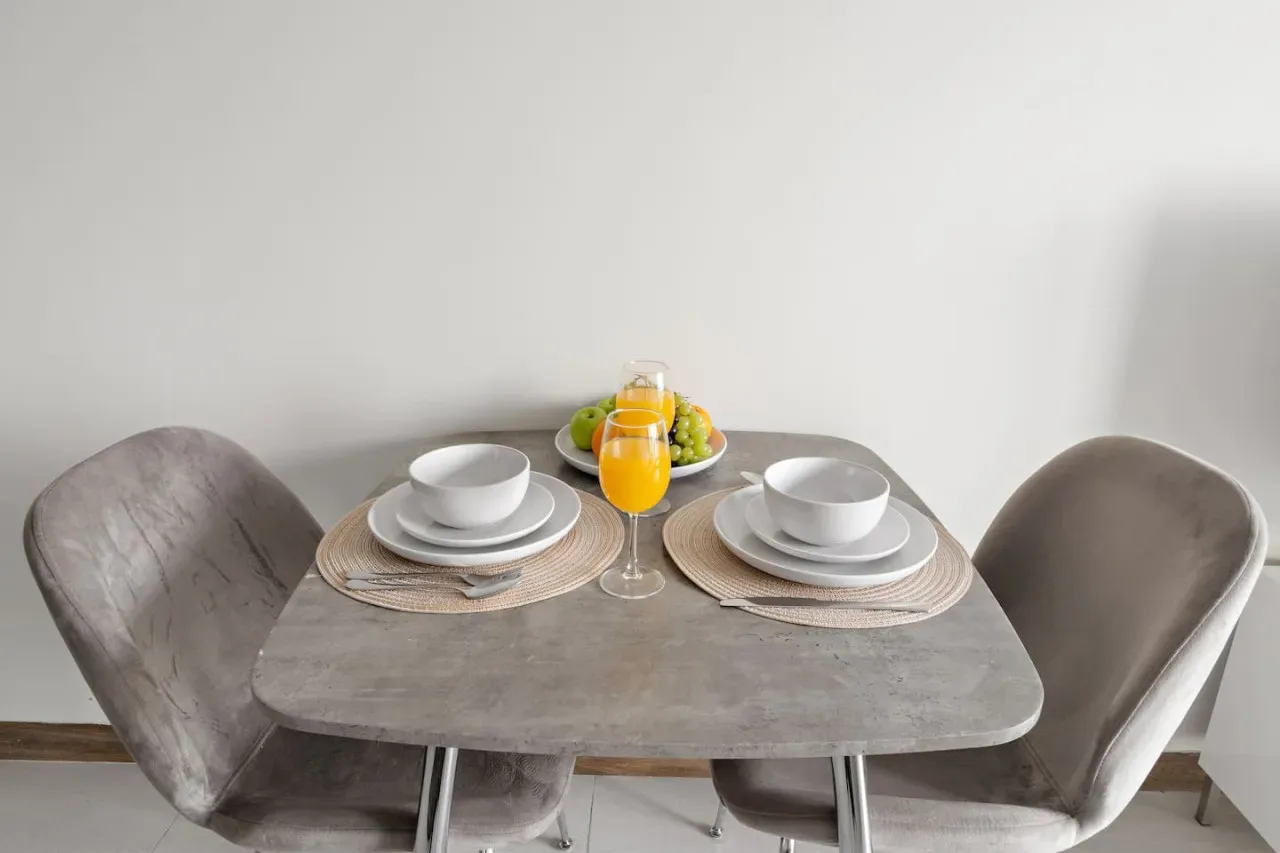 A dining area with a table set with dishes, fruit, and orange juice.