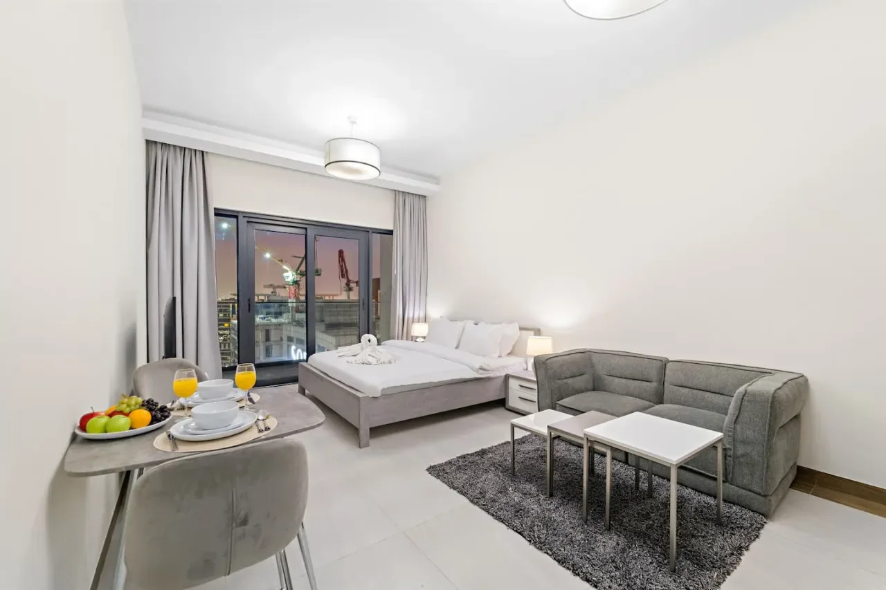 A bright bedroom and sitting area with a bed, seating, and a small dining table.