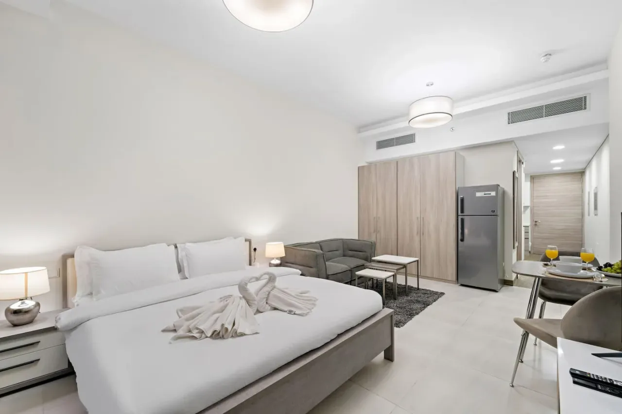 A bright bedroom with a large bed and a small seating area.
