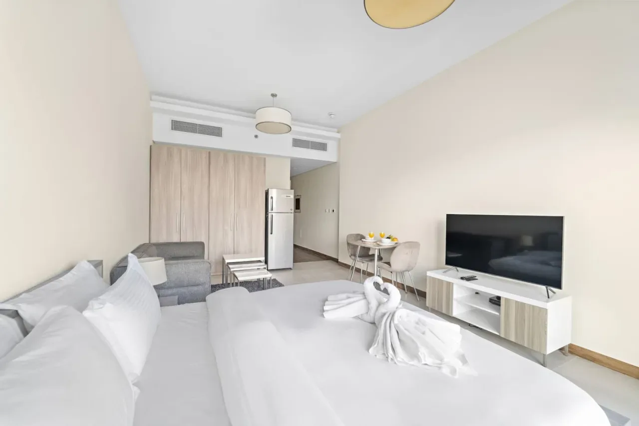 A bright bedroom with a large bed, a television, and a small seating area.
