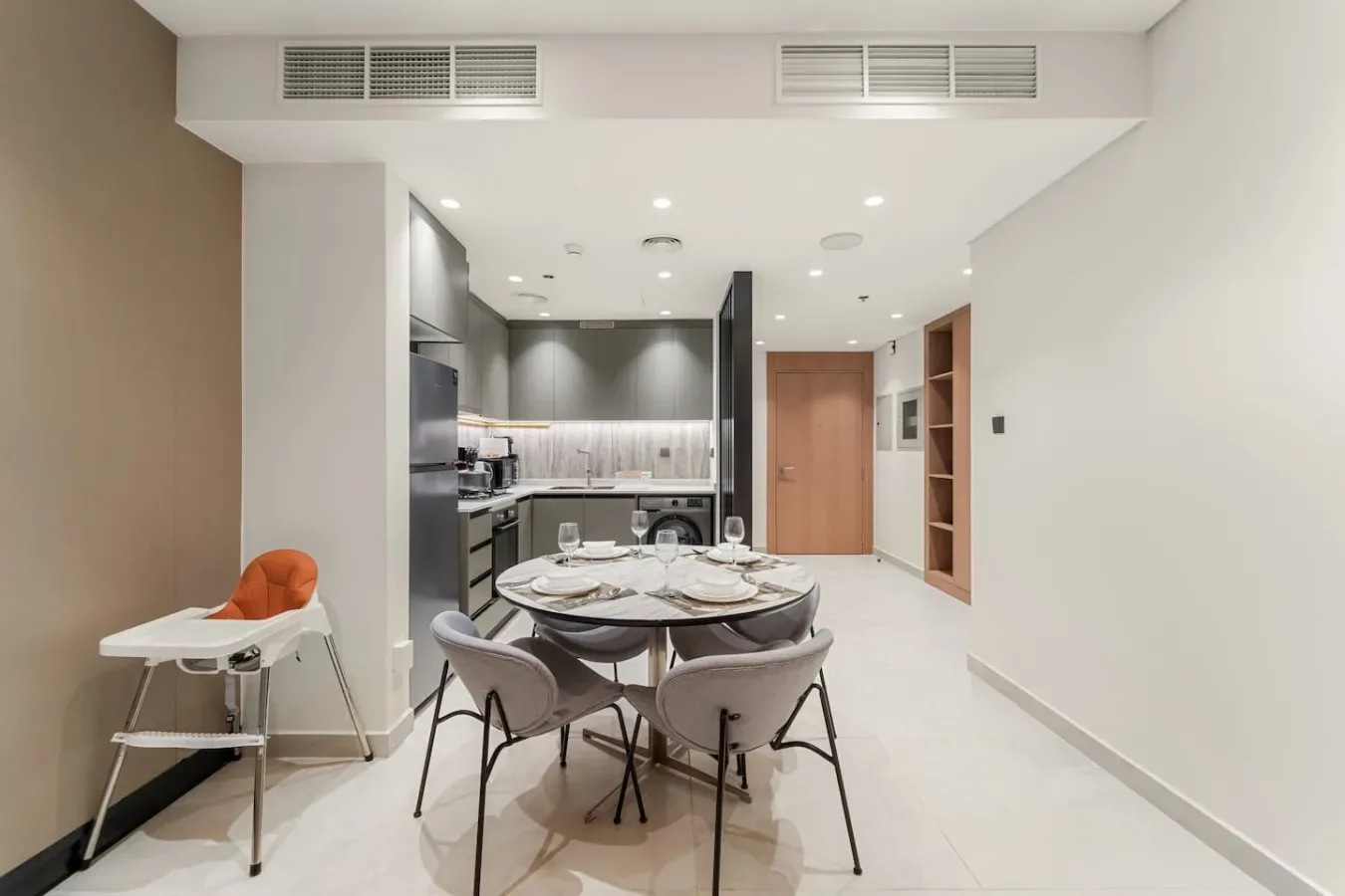 Comedor de concepto abierto y cocina, con la mesa puesta y luces empotradas en el techo.