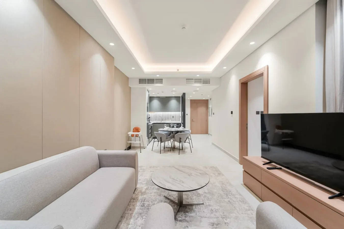 A bright living and dining area with seating, a table, and a television.