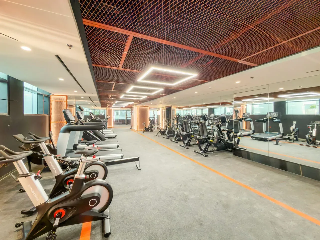 A spacious gym with exercise bikes, treadmills, and mirrored walls.