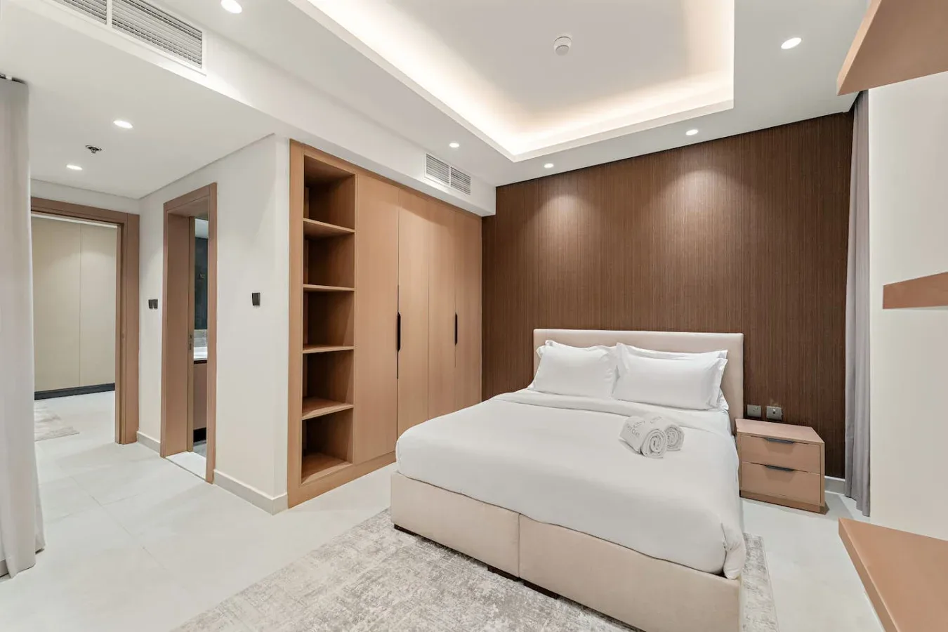 A bedroom with a neatly made bed and built-in wooden shelving.