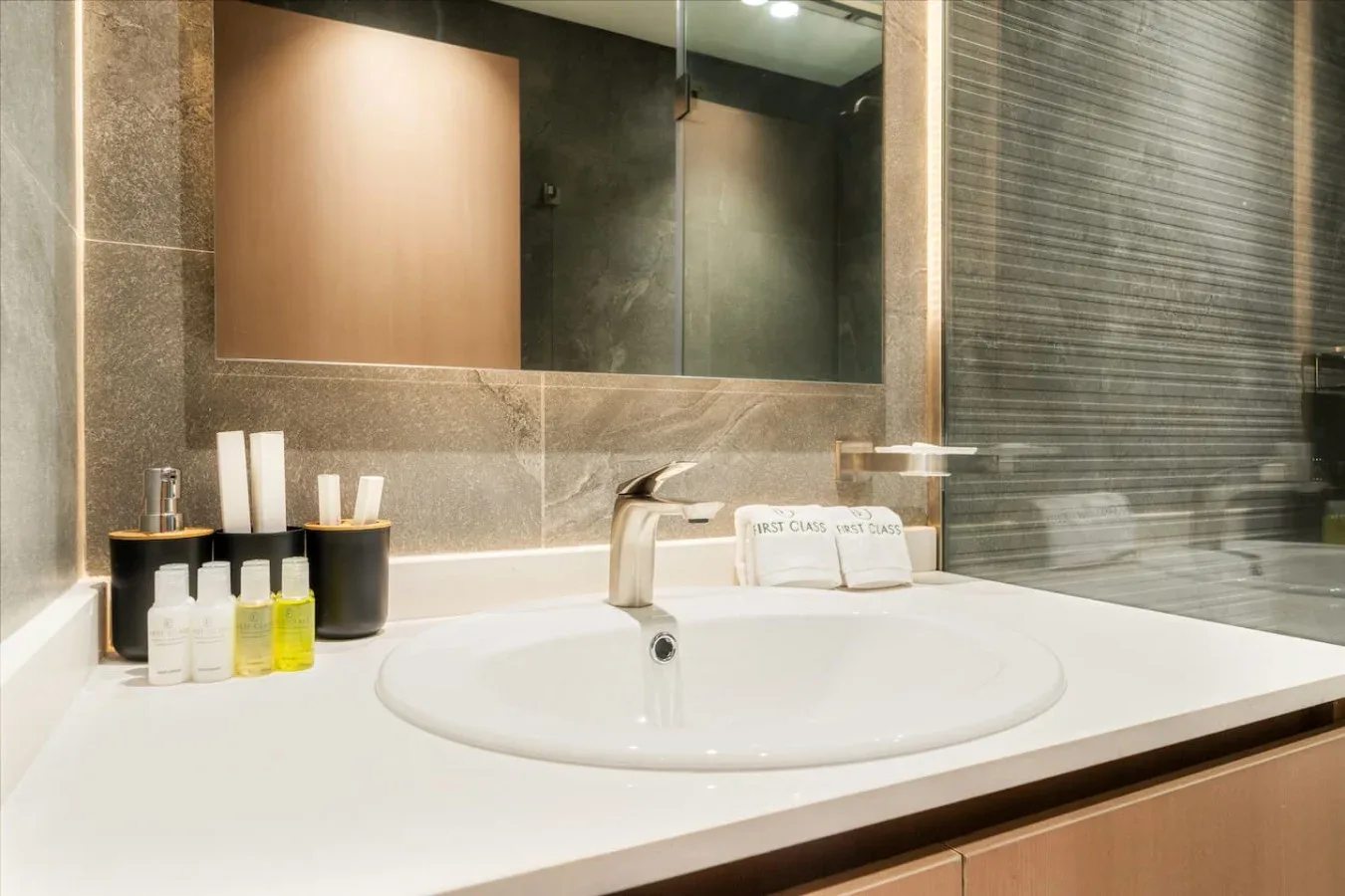 A bathroom vanity with a wide sink, wall mirror, and toiletries.