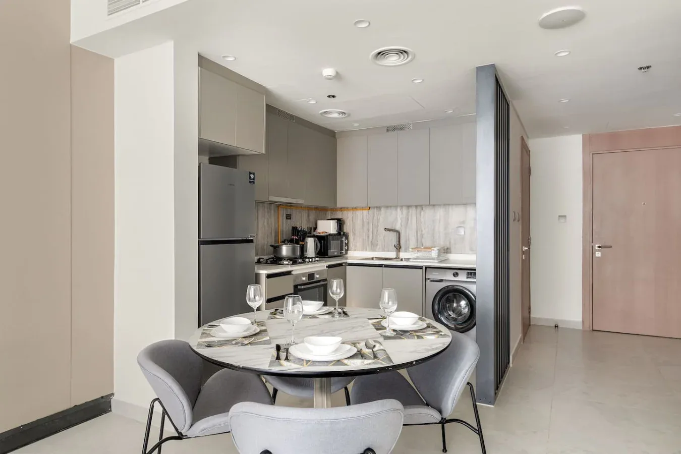 A dining area with a round table and seating beside a compact kitchen.