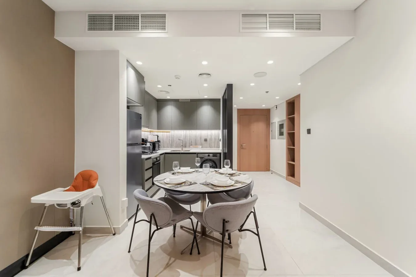 A dining area with a set table sits beside a compact kitchen.