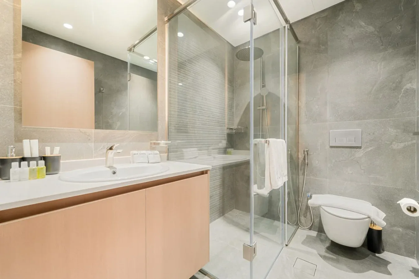 A modern bathroom with a vanity, mirror, and glass shower.