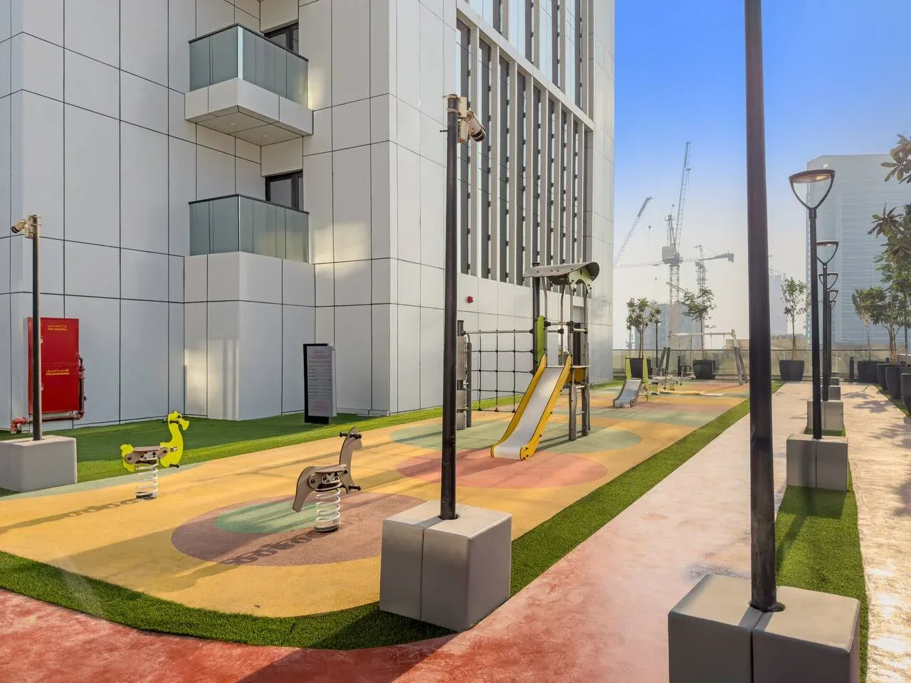An outdoor playground with colorful ground markings and play equipment beside a modern building.