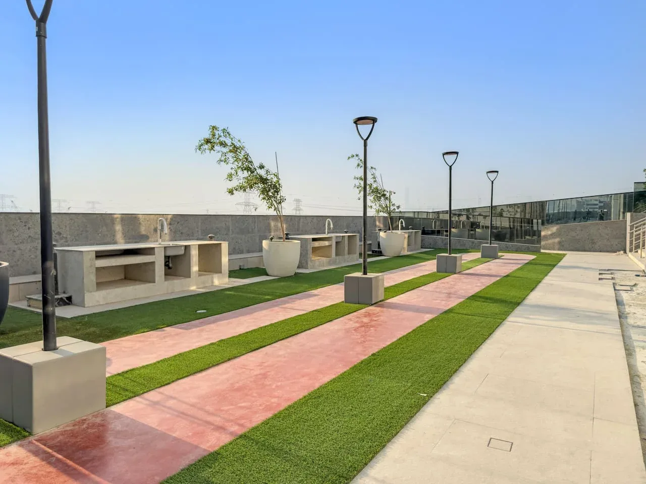 A rooftop terrace has striped green and pink paths, outdoor seating, and planters.