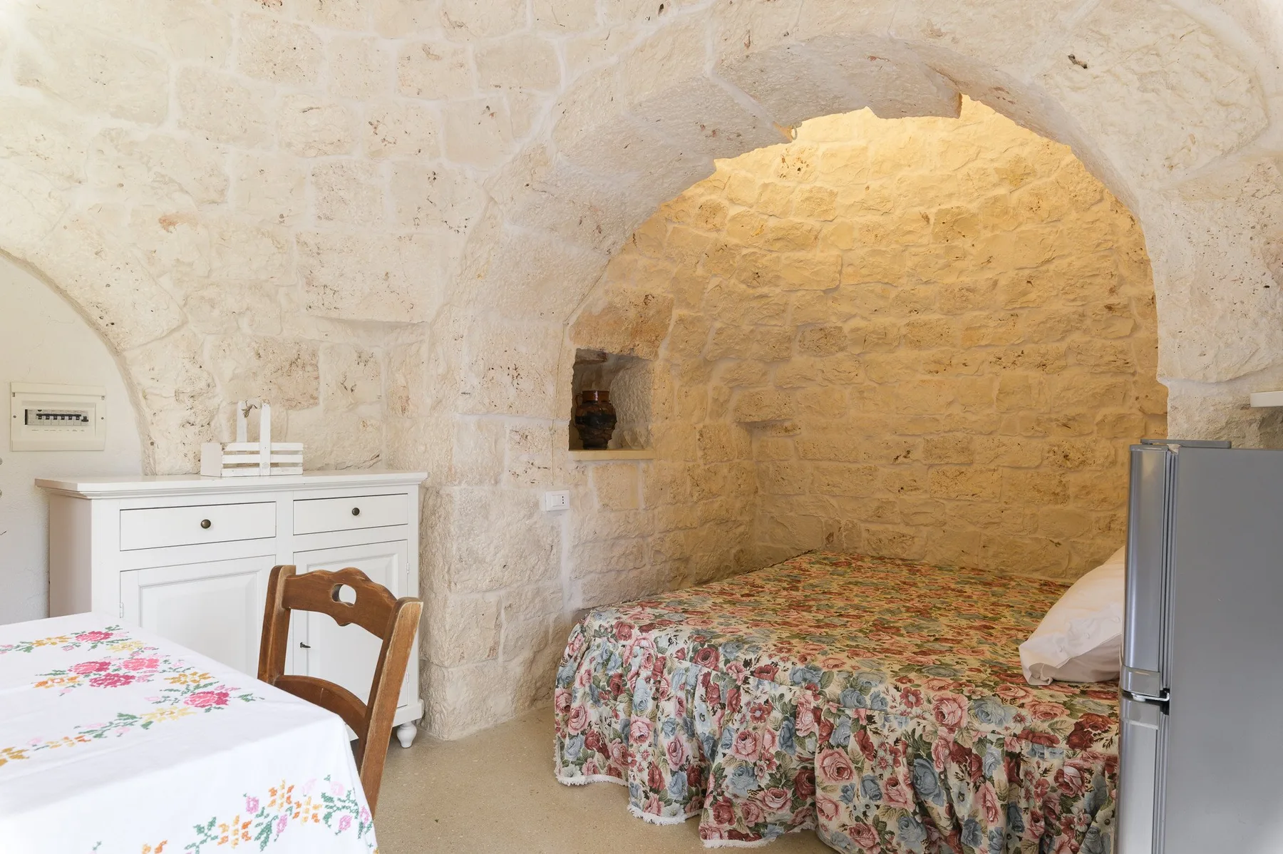 Un dormitorio con una cama cubierta de flores bajo un arco de piedra.