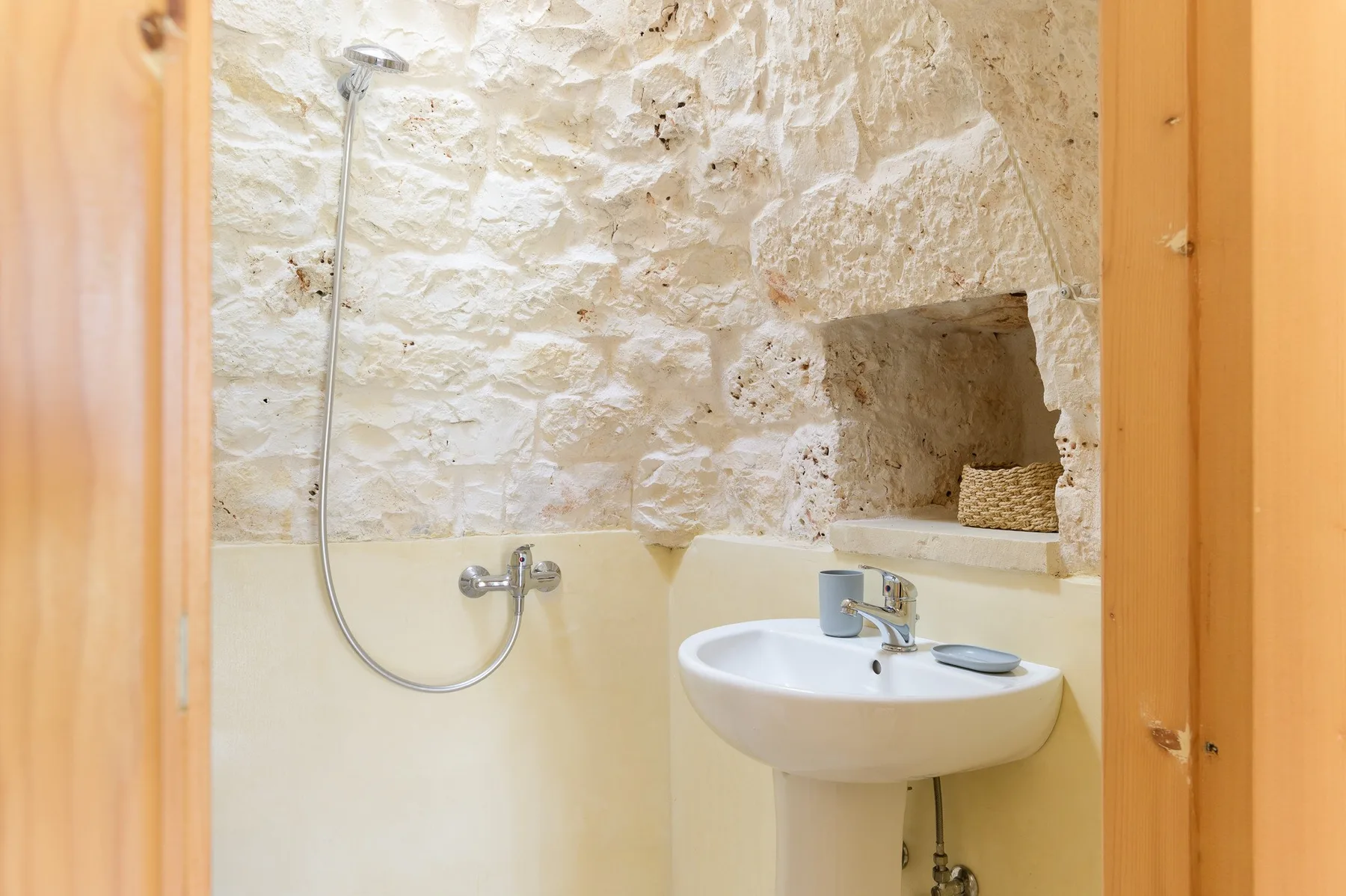 Un baño con paredes de piedra, ducha y lavabo.