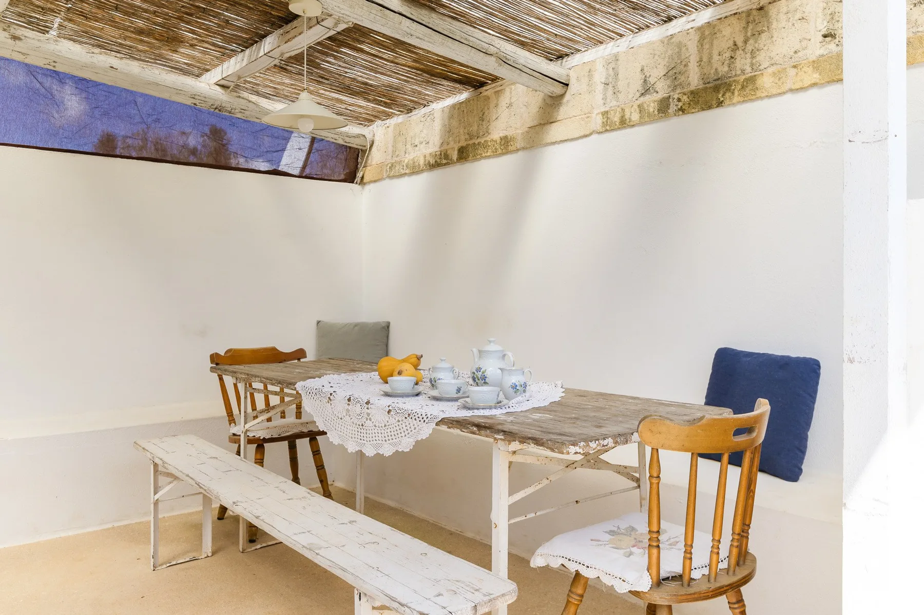 A covered dining area with a table, benches, and chairs.