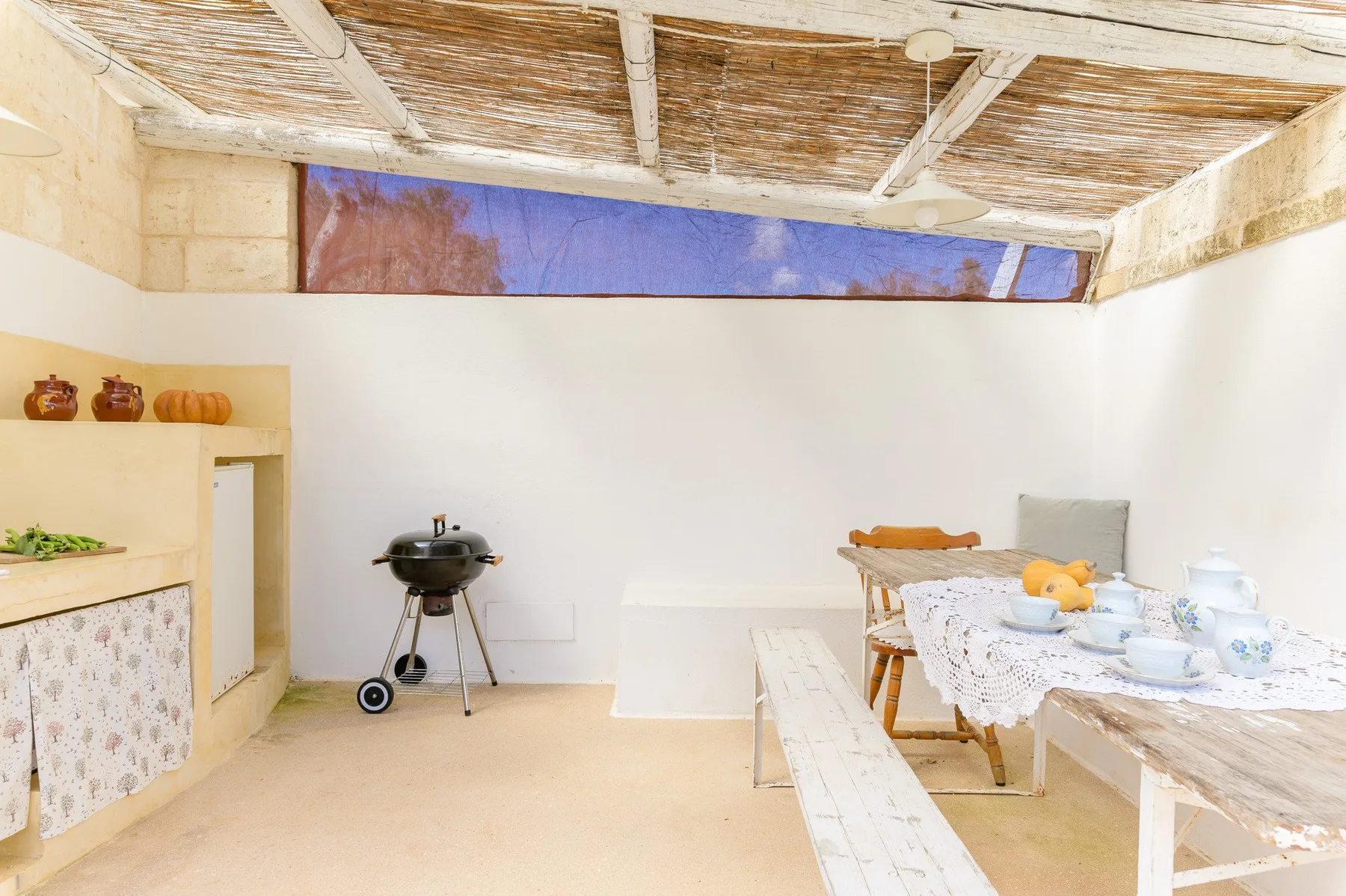 A dining area with a long table beneath a woven canopy.