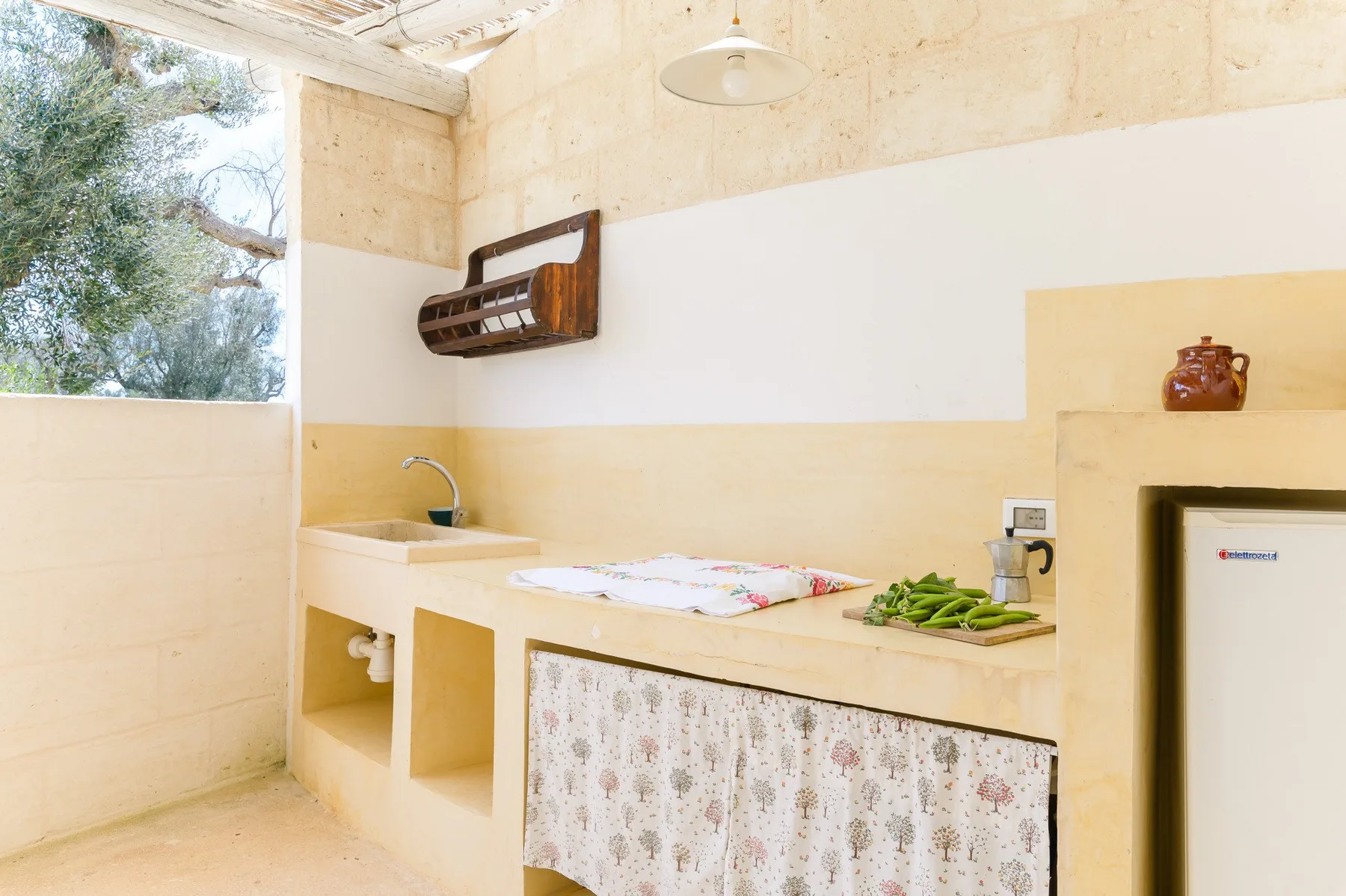 A bright kitchen with a sink, countertop, and window overlooking trees.
