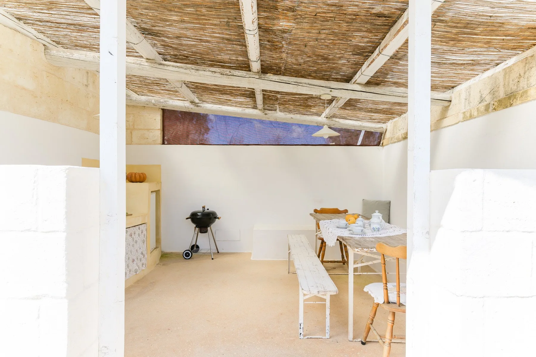 A covered dining area with a table and seating beneath a woven ceiling.