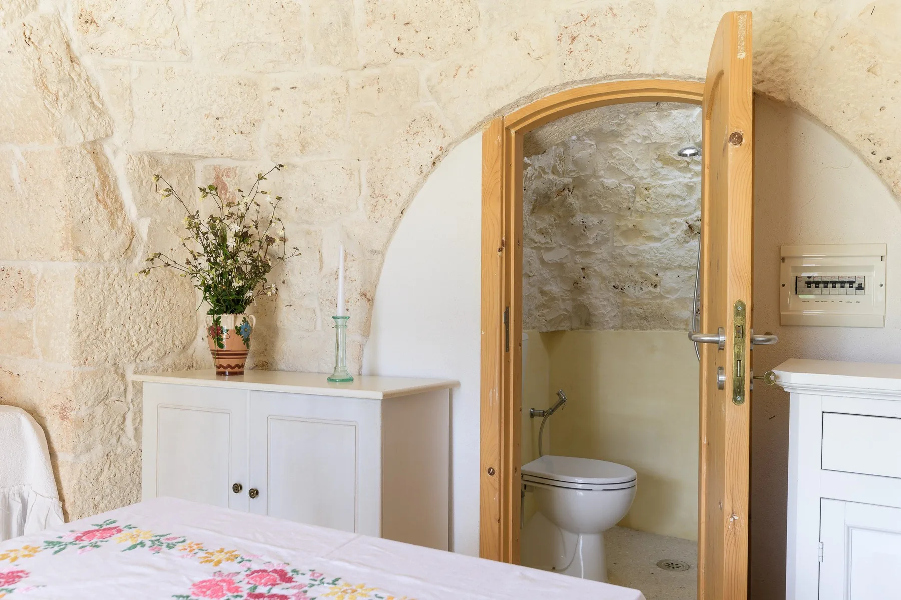 A bedroom with a floral bedspread beside an open doorway to a bathroom.