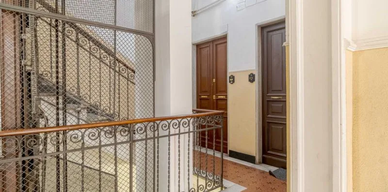 An interior stairwell with decorative metal railings and several doors.