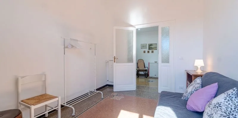 A bright bedroom with a bed, a small table, and an open doorway.