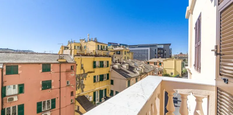 A balcony overlooks colorful city buildings beneath a clear blue sky.