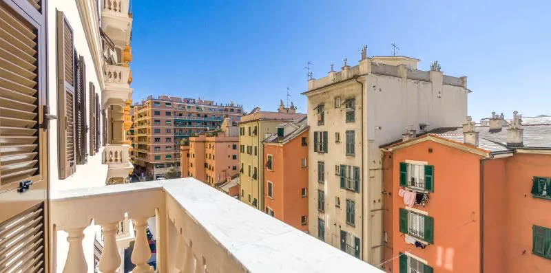 A balcony overlooks a row of colorful apartment buildings beneath a clear blue sky.