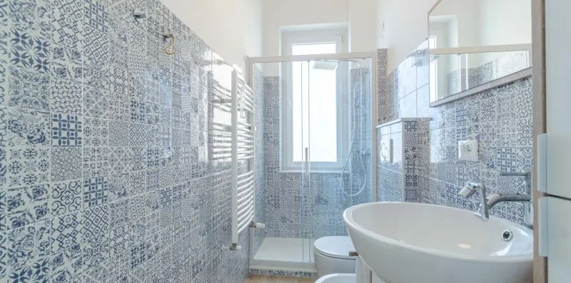 A tiled bathroom with a glass shower, toilet, and sink.