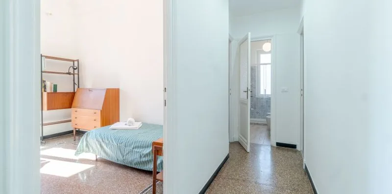 A bedroom with a bed and a hallway leading to a bathroom.