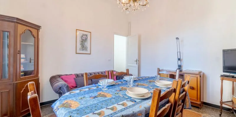 A dining room with a long table set with dishes and surrounded by seating.