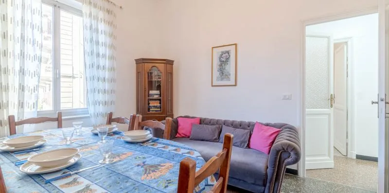 A dining area with a set table beside a living room seating area.