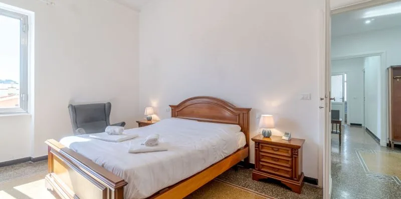 Un dormitorio con una cama bien tendida, una mesita de noche y una puerta abierta.